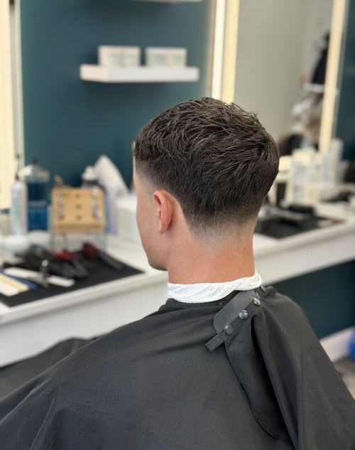 Textured taper haircut with a skin fade, back view